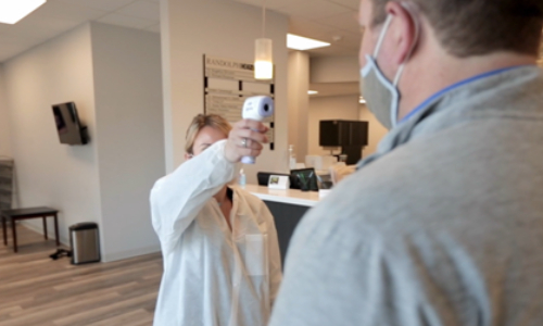 clinic staff checking patient's body temperature for covid safety